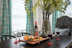 A dining table set with a fruit platter, wine glasses, and a bottle of wine. - Big House on Highland: Your Country Escape (Abilene)