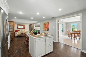 Une cuisine spacieuse avec un coin repas, un plancher en bois et une vue sur la salle à manger.