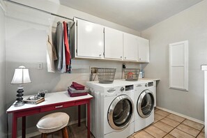 Une buanderie équipée d’un lave-linge, d’une table avec une lampe et d’une chaise.