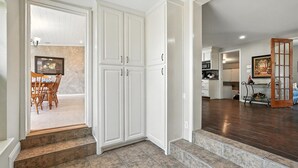 Une cuisine avec des meubles blancs, un coin repas comprenant une table et des chaises, et un escalier menant à un autre niveau.