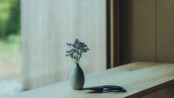 A wooden shelf with a vase of purple flowers and a pair of scissors.