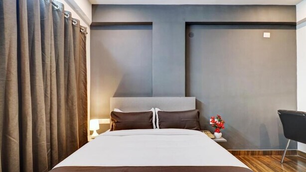 Ein modernes Hotelzimmer mit einem großen Bett, einem Nachttisch, einer Lampe und einem kleinen Tisch mit Blumen.