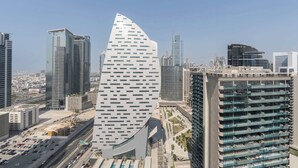 Um edifício moderno e imponente com um design curvo distinto, rodeado por outros edifícios altos em um ambiente urbano.