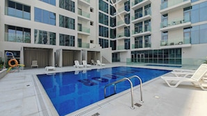 A modern indoor swimming pool with multiple levels of balconies, lounge chairs, and a lifebuoy.