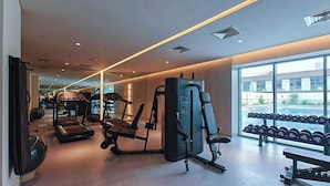 A modern gym with treadmills, weight machines, and dumbbells.