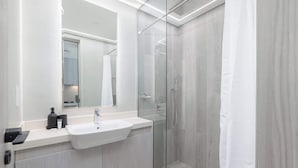 A modern bathroom with a glass-enclosed shower, a white sink, and a large mirror.