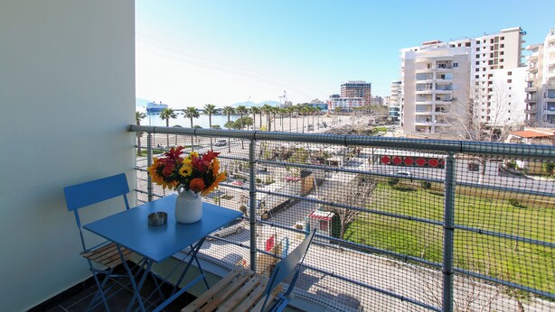 A balcony with a table, chairs, and a vase of flowers. - Seascape Apartments Vlore (Vlore)