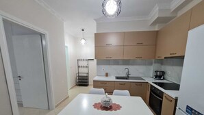 A compact kitchen with a dining table, chairs, a sink, and a stove. - Seascape Apartments Vlore (Vlore)