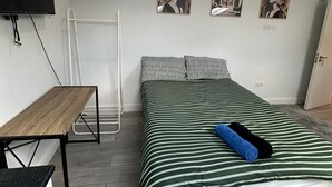 A bedroom with a bed, a desk, and a TV mounted on the wall. - Bright Studio in Thornton Heat (Thornton Heath)
