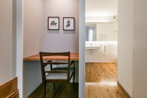A hallway leading to a bathroom with a wooden floor, a sink, and a towel hanging on the wall.