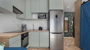 A compact kitchen with a built-in microwave, stainless steel refrigerator, and a coffee maker.