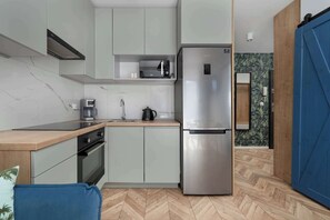 Una cocina compacta con microondas integrado, refrigerador de acero inoxidable y cafetera.