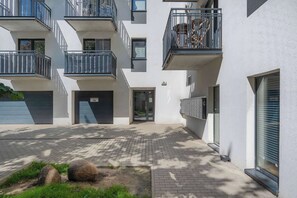 Un edificio residencial de varios pisos con balcones, un acceso mediante portón y un patio empedrado.