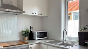 Een moderne keuken met witte kastjes, een roestvrijstalen afzuigkap, een magnetron en een spoelbak.