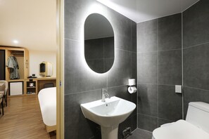Une salle de bain moderne avec un grand miroir ovale, un lavabo blanc et des toilettes.