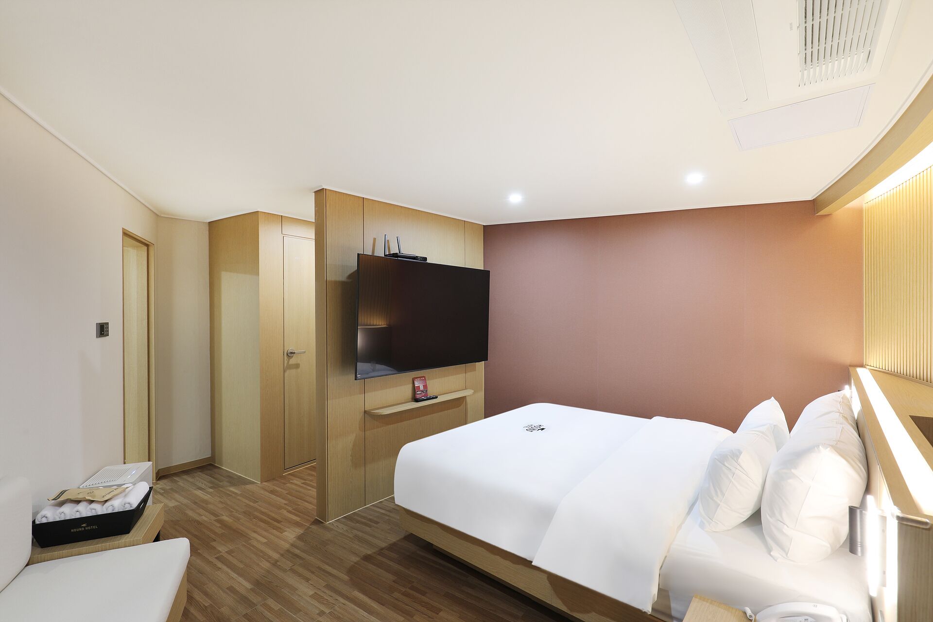 A hotel room with a bed, a TV, a wardrobe, and a bedside table.