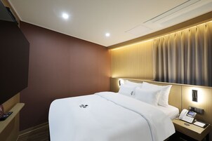 Una habitación de hotel con cama, mesita de noche y teléfono en la pared.