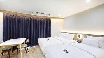 A hotel room with two beds, a desk, a chair, and a large window with curtains.