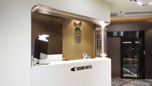 A hotel reception desk with a modern design, a clock, and a sign indicating free Wi-Fi.