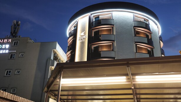 A modern hotel with a circular design, multiple balconies, and illuminated signage.