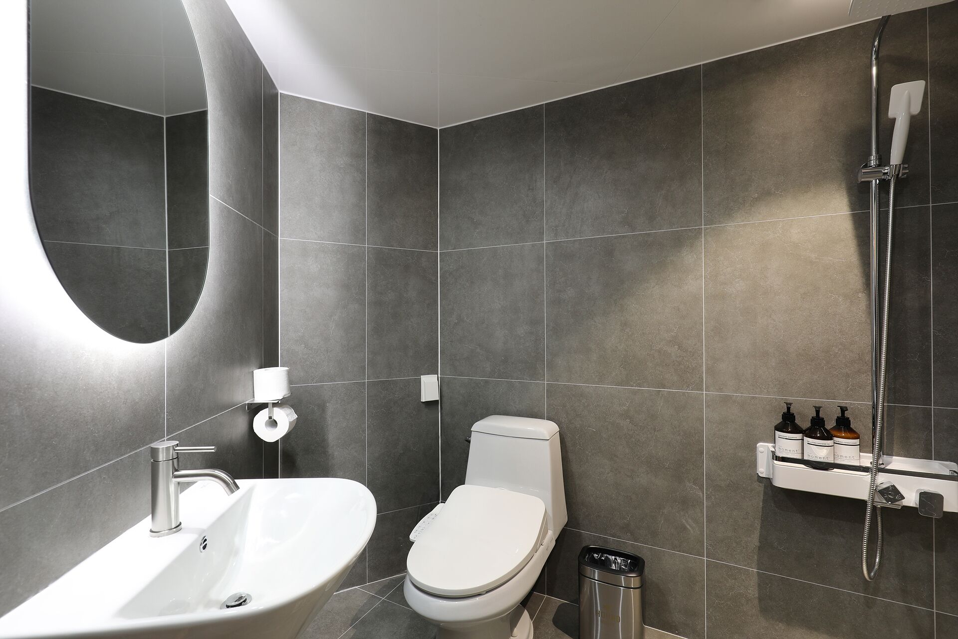 A modern bathroom with a white sink, toilet, and shower.