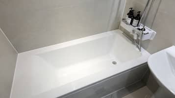 A modern bathroom with a white bathtub, a shower, and a sink.