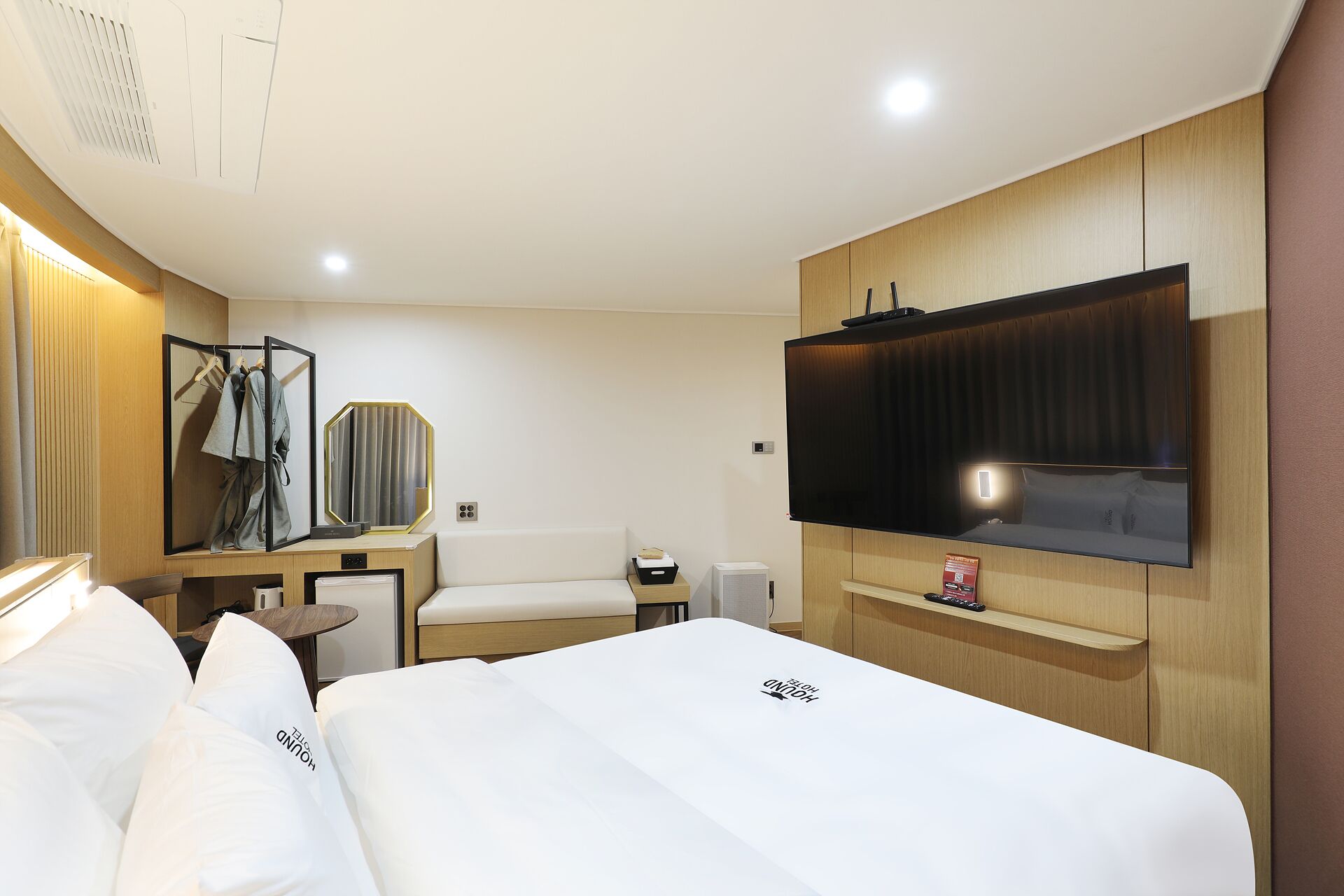 A hotel room with a bed, a TV, a desk, and a mirror.