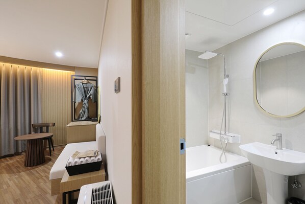 Una habitación de hotel con cama, una mesa con toallas, ducha y lavamanos.