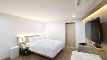 Una camera d'albergo con un letto, un comodino, una televisione e una scrivania con una sedia.