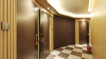 A hallway with checkered flooring, wooden panel walls, and a fire extinguisher.