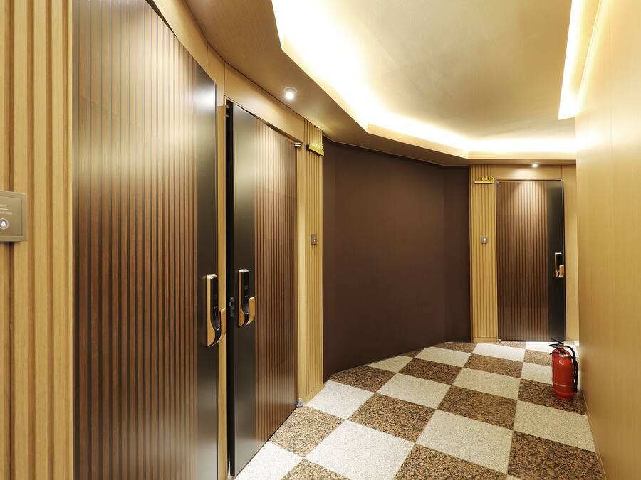A hallway with checkered flooring, wooden panel walls, and a fire extinguisher.