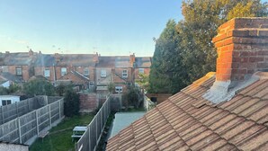 Ett bostadsområde med radhus, en inhägnad trädgård och en klar himmel.