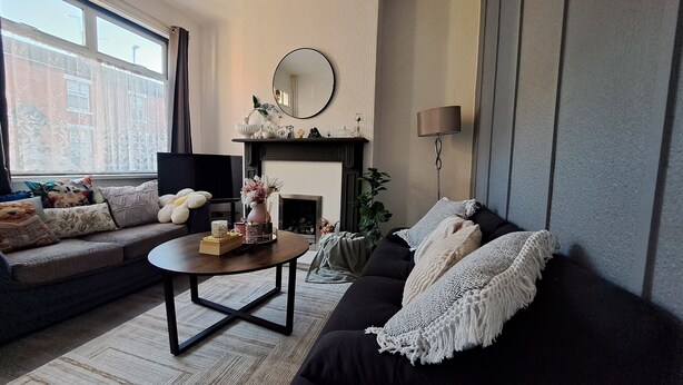 A living room with a sofa, a coffee table, a fireplace, and a television.