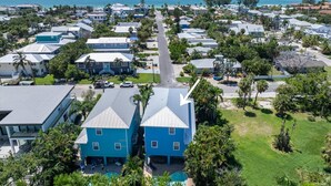 A coastal residential area with houses, a clear view of the ocean, and a central road. - Blue Haven Beach House: 3BR/3BA Pool Home Steps to Beach (Holmes Beach)