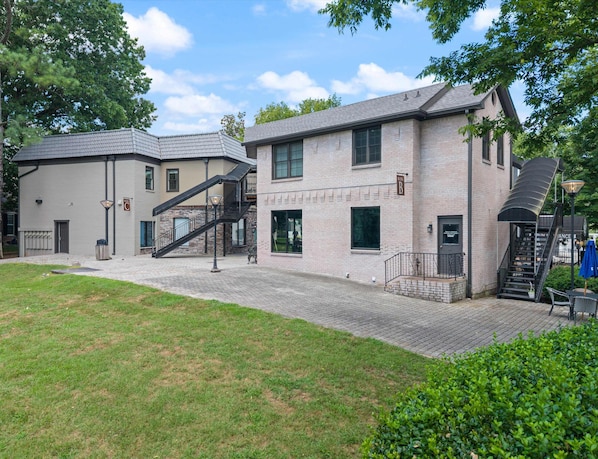 A two-story building with a brick facade, a staircase, and a paved courtyard.