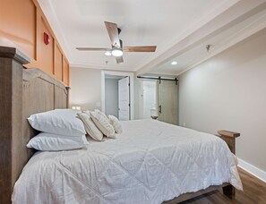Una camera da letto con un letto, una ventola a soffitto e una porta che dà su un bagno.