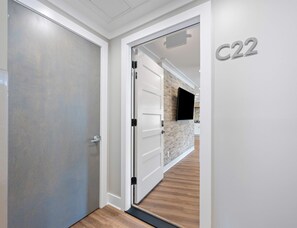 Un pasillo de diseño moderno, con una puerta blanca, una puerta con pomo negro y un cartel con número en la pared.