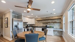 A modern kitchen with a central island, white cabinetry, and a brick backsplash. - Carters Court Serene Suite (Franklin)