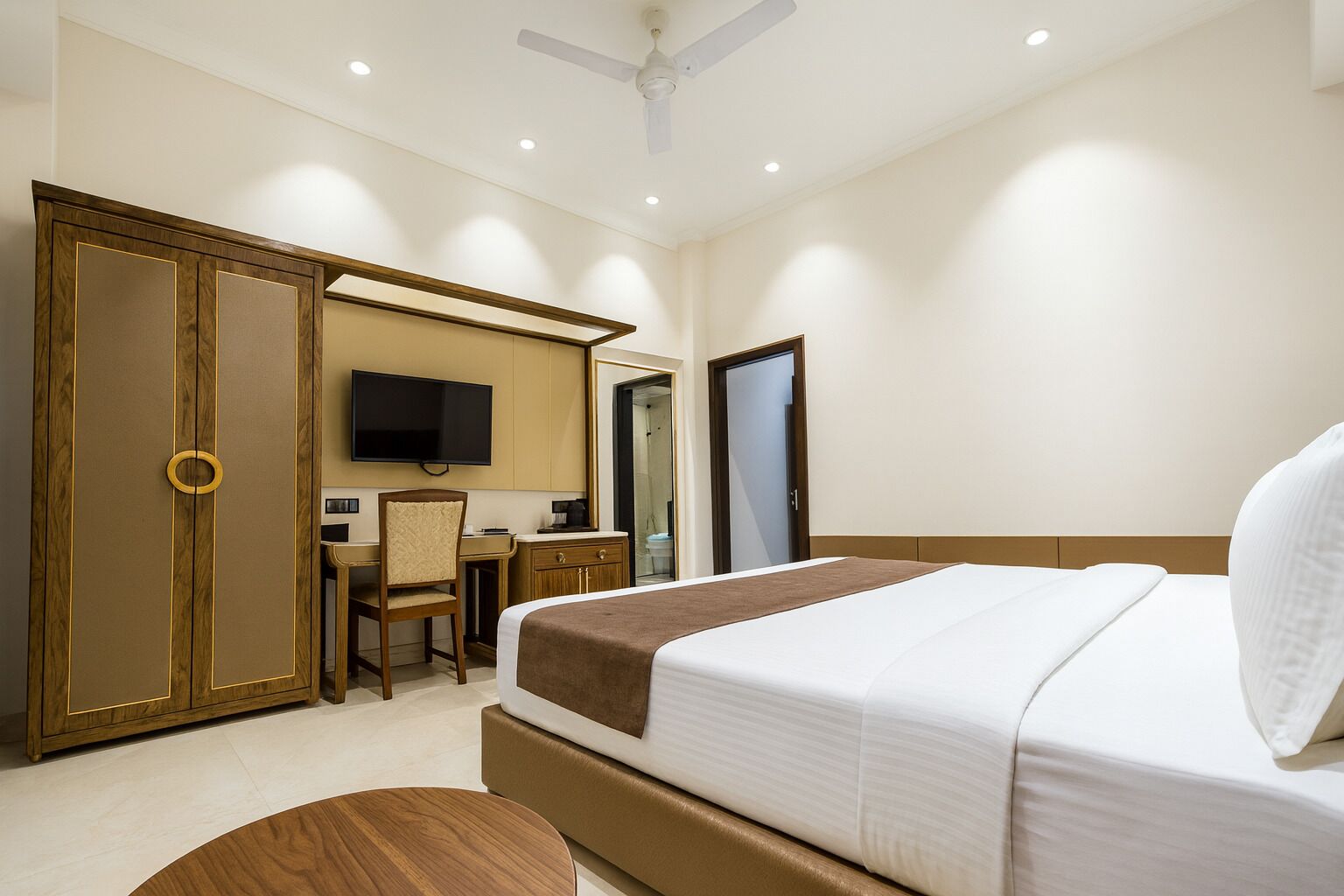 Una habitación de hotel con cama, escritorio, silla, armario y televisor.