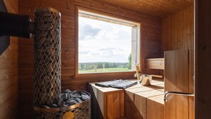 A wooden cabin interior with a stone fireplace, a window with a view, and a wooden cabinet. - Private Airplane Lodge - Sauna & outdoor jacuzzi (Uurainen)