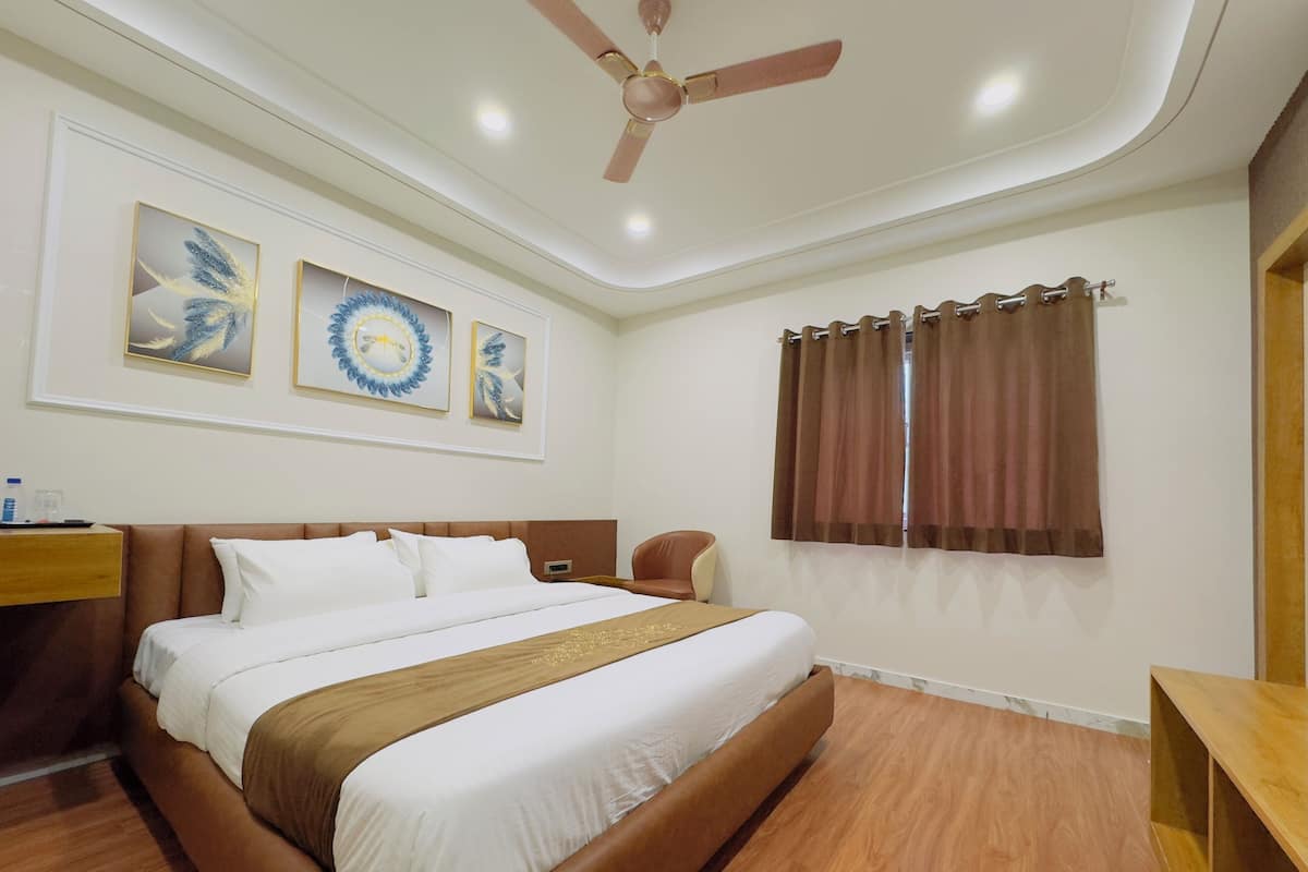 A hotel room with a bed, a wooden headboard, a ceiling fan, and artwork on the wall.