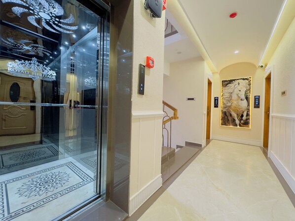 A hotel entrance with a glass door, a staircase, and a hallway leading to rooms. - Royale Heritage (Ujjain)