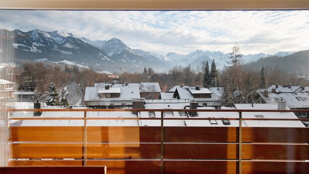 A view of snow-covered mountains and buildings through a window. - Holiday Apartment 'Nini's Berge' with Panoramic View, Shared Garden and Wi-Fi (Sonthofen)