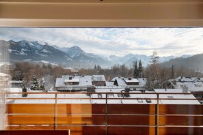 A view of snow-covered mountains and buildings through a window.