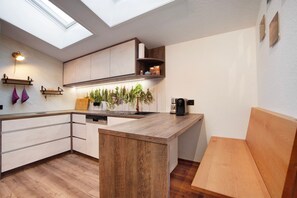 Eine moderne Küche mit Oberlichtern, Holzschränken, einem eingebauten Geschirrspüler und einer Kaffeemaschine.
