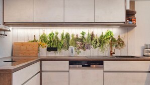 A modern kitchen with a built-in dishwasher, wooden countertop, and a variety of herbs hanging above the sink. - Holiday Apartment 'Nini's Berge' with Panoramic View, Shared Garden and Wi-Fi (Sonthofen)