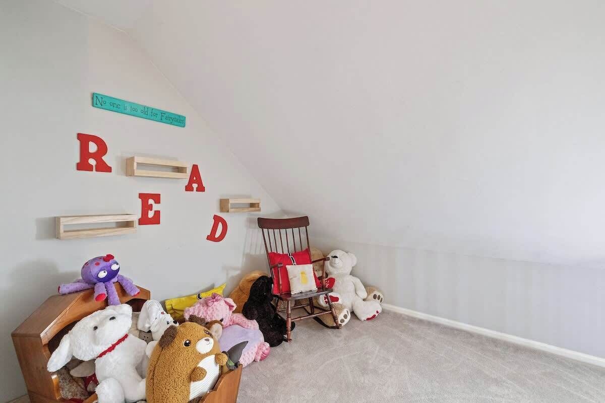 A child's room with alphabet letters on the wall, a wooden chair, and stuffed animals.