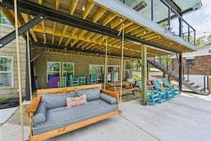 Un espacio al aire libre techado con un sillón colgante, mesas de picnic y sillas azules.