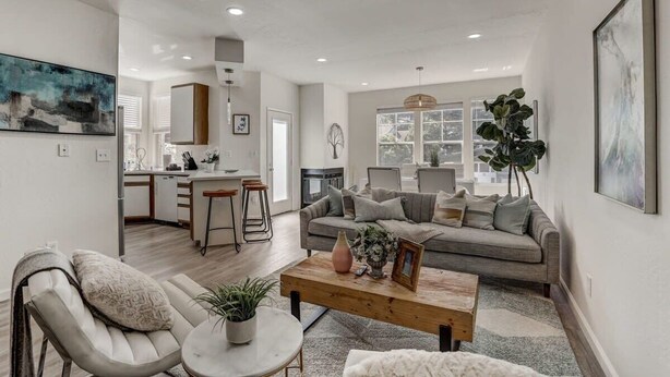 A spacious living area with a grey sofa, a coffee table, and a dining area in the background. - @ Marbella Lane - Modern 3BR Home w/ Ocean Views (Pacifica)