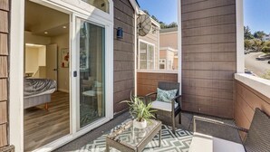 A balcony with a wicker coffee table, a chair, and a potted plant. - @ Marbella Lane - Modern 3BR Home w/ Ocean Views (Pacifica)